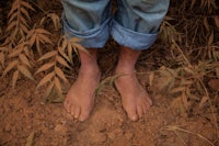 a man's bare feet standing in the dirt