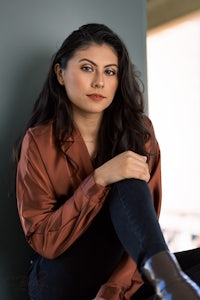 a woman in a brown shirt sitting on a wall