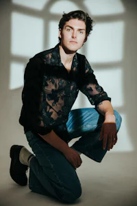 a young man crouching down in front of a window
