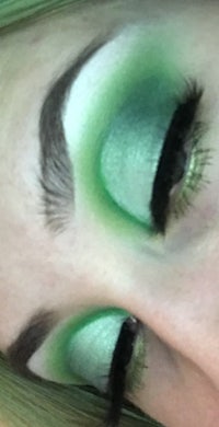 a close up of a woman's green eye makeup