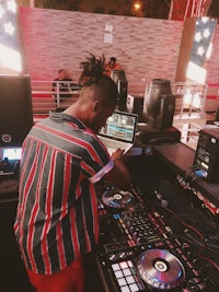 a man with dreadlocks working at a dj booth