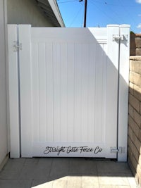 a white gate in front of a brick wall