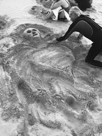 a group of people working on a sand sculpture on the beach