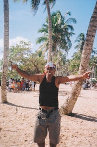 a man standing on a beach with his arms outstretched