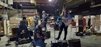 a group of people playing guitars in a warehouse