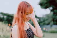 a girl with red hair is posing in a park