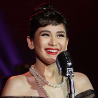 a woman in a black dress is smiling while holding a microphone