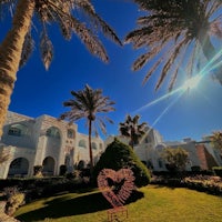 a white building with palm trees and a heart shaped statue