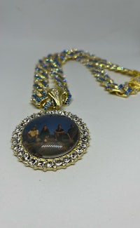 a gold and blue necklace with a picture on it