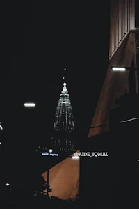 a city at night with a tall building in the background