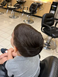 a young boy sitting in a chair in a hair salon
