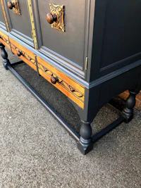 a black and gold painted sideboard with drawers