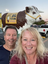 two people standing in front of a big texas bull statue