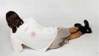 a woman laying on the floor wearing a white t - shirt with a pink star on it