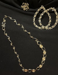 a gold necklace and bracelet set on a black cloth