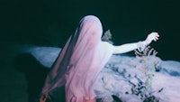 a woman wearing a veil is standing on a rock