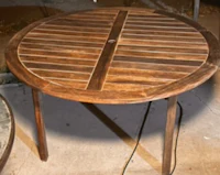 a round wooden table with two chairs on it