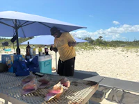 a man on a beach grilling conch