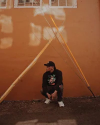 a man kneeling in front of an orange wall