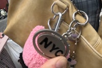 a person is holding a pink bag with a keychain on it