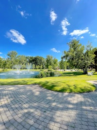 a brick walkway leads to a pond in a park