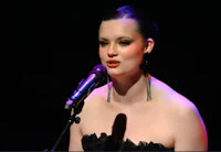 a woman in a black dress singing into a microphone