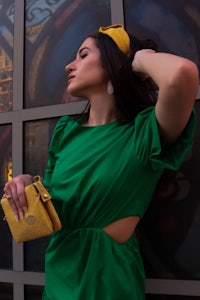a woman in a green dress leaning against a wall