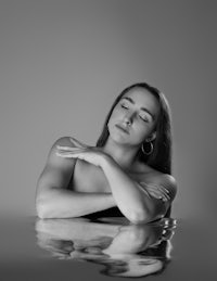 a black and white photo of a woman laying in water