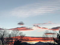 a sunset with clouds and mountains in the background