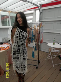 a woman in a crocheted dress standing on a deck