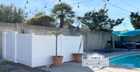 a backyard with a white fence and potted plants