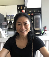 an asian woman smiling in front of a coffee shop