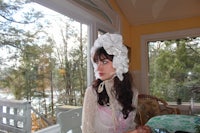 a woman wearing a white hat in front of a window