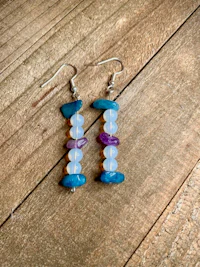 a pair of earrings with blue, purple, and green stones