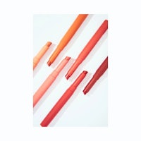 a set of five orange lipsticks on a white surface