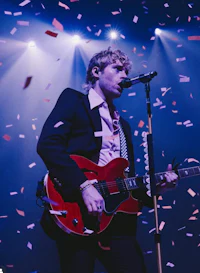 a man playing an electric guitar in front of confetti