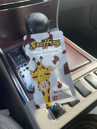 a giraffe sitting on the steering wheel of a car