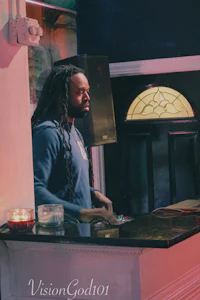 a man with dreadlocks standing in front of a bar