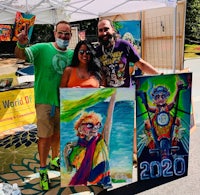 three people posing for a photo with their paintings