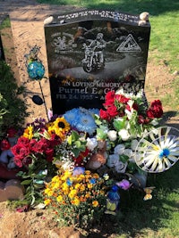 a gravestone with flowers and a wind chime