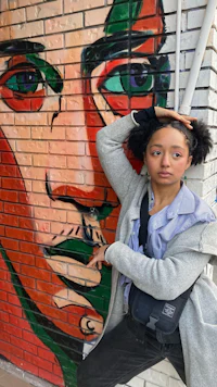 a woman leaning against a brick wall with a face painted on it
