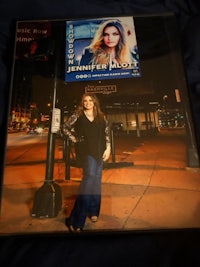 a woman standing on a street corner with a poster