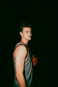 a young man holding a basketball in the dark