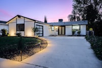 a home with a driveway and lights at dusk