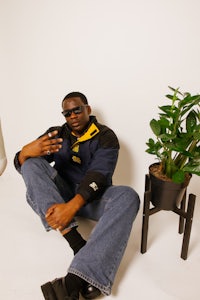 a man sitting on the floor with a plant