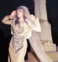 a woman dressed as a bride in front of a tombstone