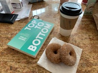 two donuts on a napkin next to a cup of coffee