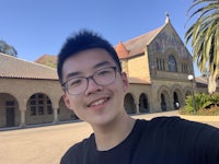a man with glasses is taking a selfie in front of a building