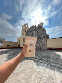 a person holding up a bag of coffee in front of a building