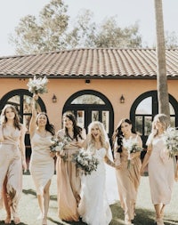 the bride and her bridesmaids are walking in front of a house